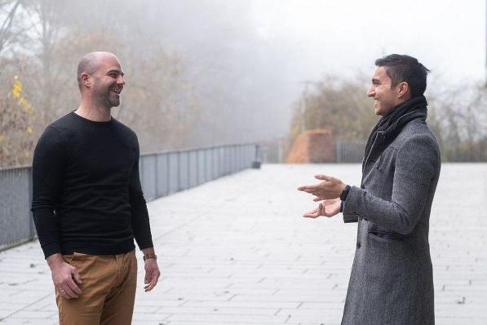 Professor Dr. Stefan Bauernschuster und Student Edwin Mejía im Gespräch auf dem Campus der Uni Passau.